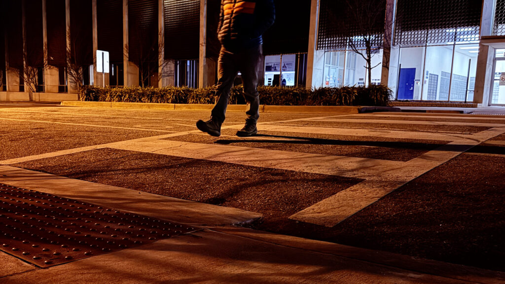 A pedestrian crossing the street at night.