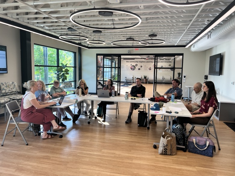 The 2025 BWG Board of Directors sits around a U-shaped table at a quarterly board meeting at the lovely and modern Prisma Health Adaptive Cycling and Wellness Facility in Unity Park